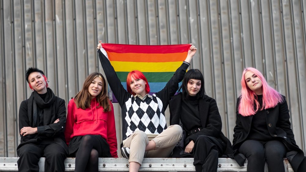 A Pride group posing with a rainbow flag